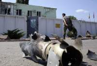 A Ukrainian border guard passes the remains of a grenade in Milove, Lugansk oblast. ©AFP